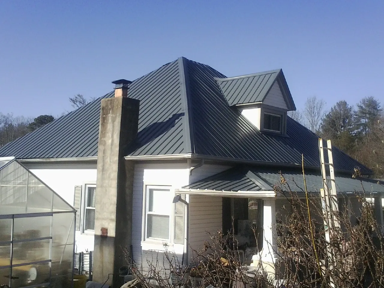 Dark blue standing seam metal roof on a white farmhouse with dormer — Slate & Tile Roof Repair by Roofing Brothers in Scarville