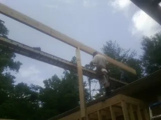 Carpenter setting a ridge beam over a new addition frame — Ice Dam Removal by Roofing Brothers in Scarville