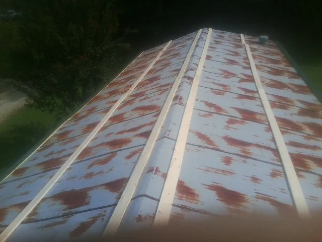 Rusted metal roof panels with new wood purlins before replacement — Storm Damage Roof Repair in Scarville by Roofing Brothers