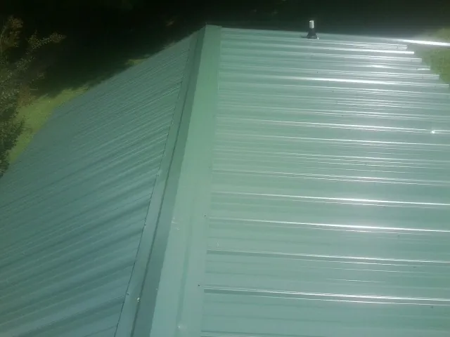 New green metal panels meeting at the ridge of a roof — Flat Roof Repair work by our crew in Scarville