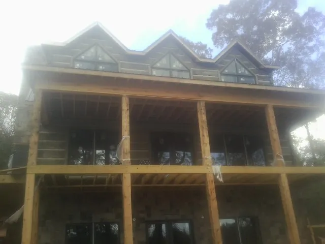 Dormers and porch framing on a large log home under construction — Roof Coating work by our crew in Scarville
