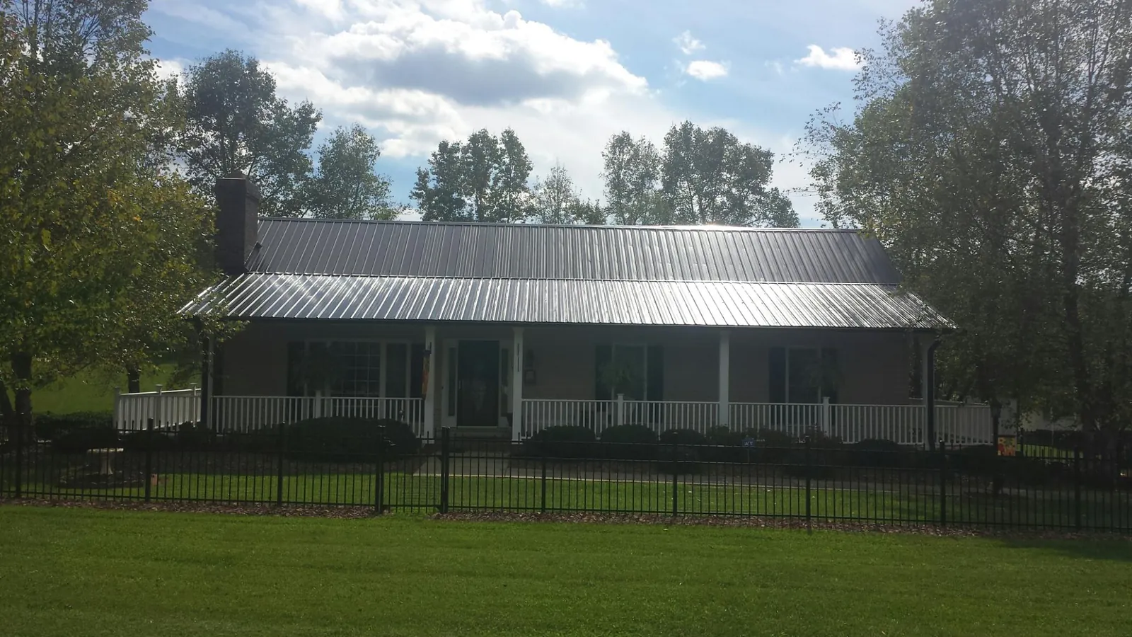 Gray metal roof on a brick ranch with a full width front porch — Gutter Guard Installation work by our crew in Scarville