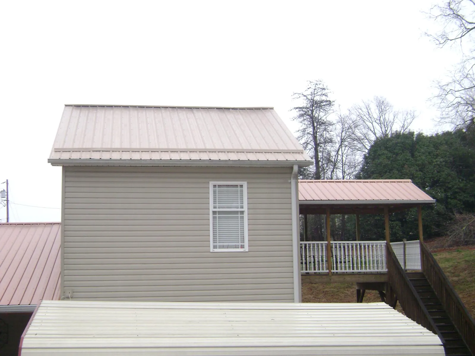 Tan metal roofs on a two story addition and attached porch, from a Roof Replacement job in Scarville