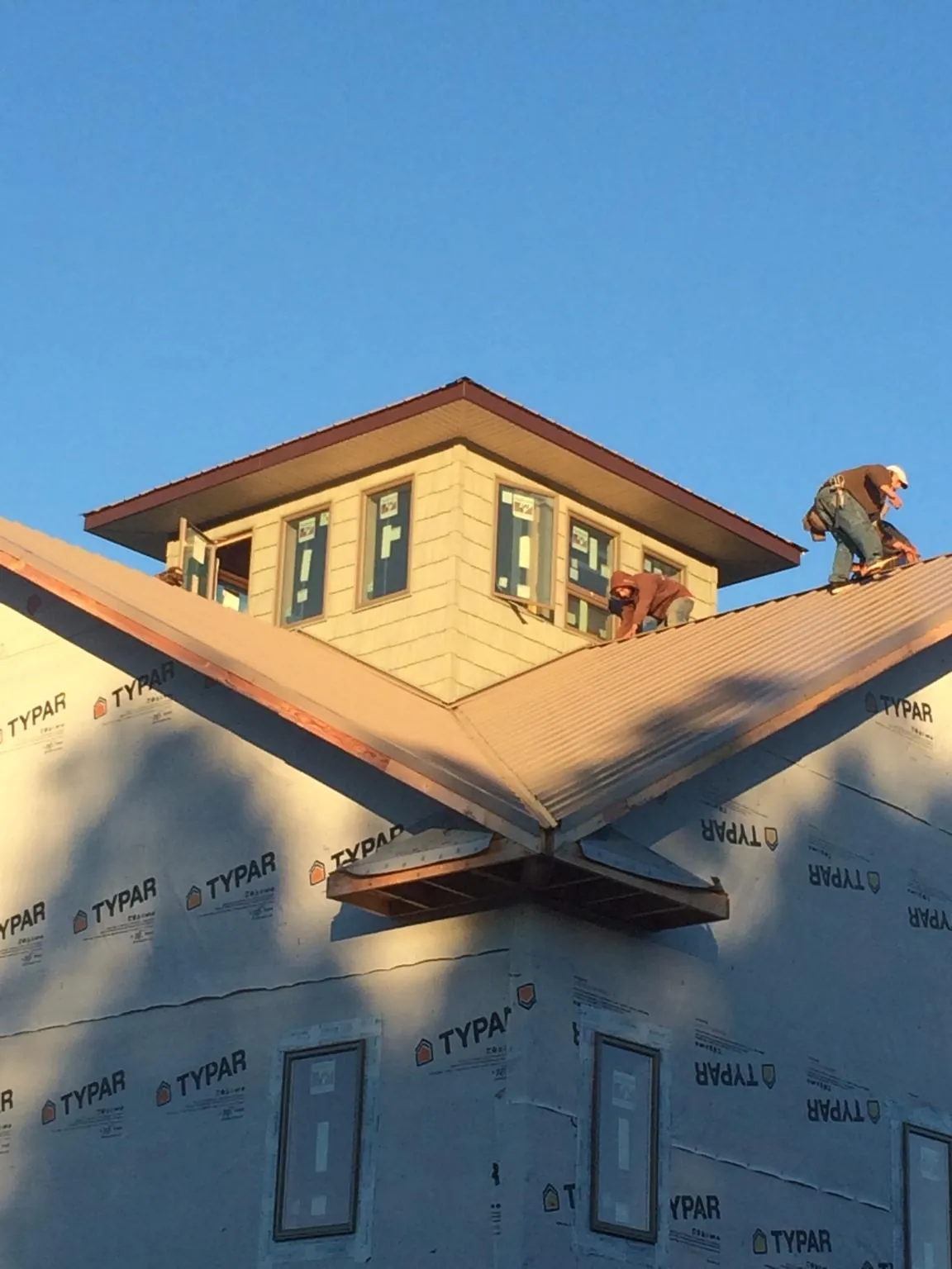 Roofers working around a rooftop cupola on a new metal roof at sunset — Roof Waterproofing in Scarville by Roofing Brothers